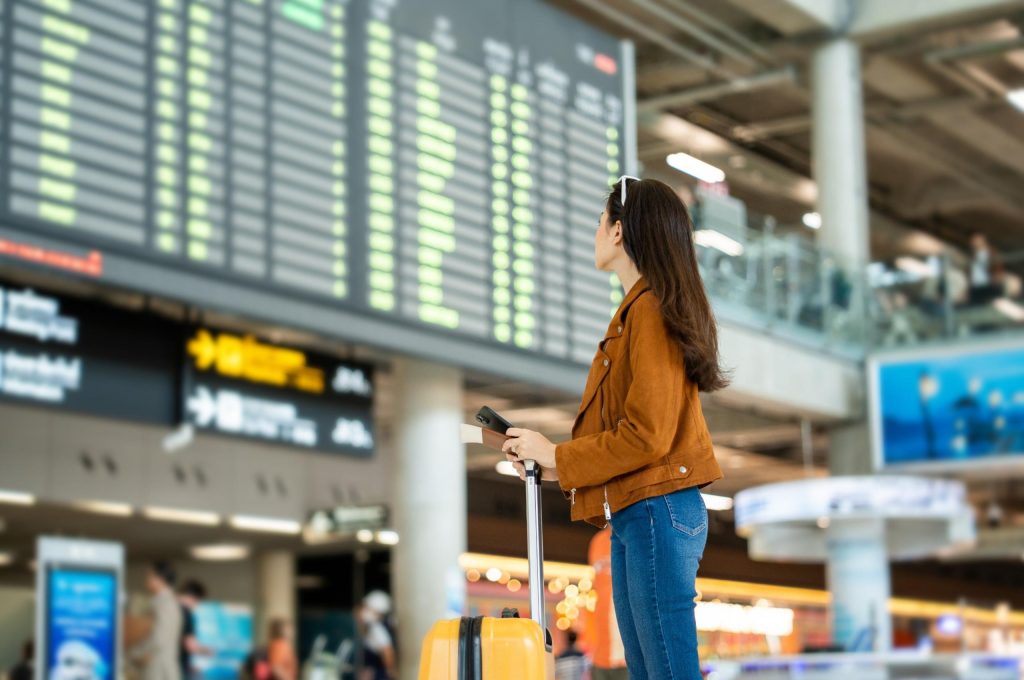 A woman looking at a departure board in an airport.